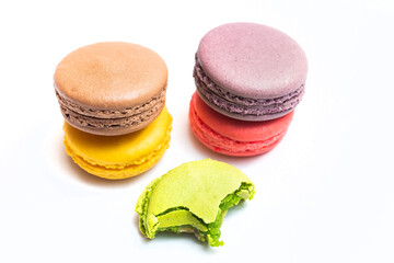 Bitten macaron and Various flavors of pastel macarons stacked against isolated on white background....