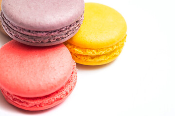 Various flavors of pastel macarons stacked against isolated on white background. Macarons is a delicate meringue-based cookie sandwich It is a dessert of French origin.