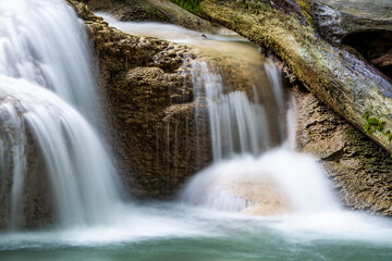 Fototapeta premium Waterfall and blue emerald water color in Erawan national park. Erawan Waterfall, Beautiful nature rock waterfall steps in tropical rainforest at Kanchanaburi province, Thailand
