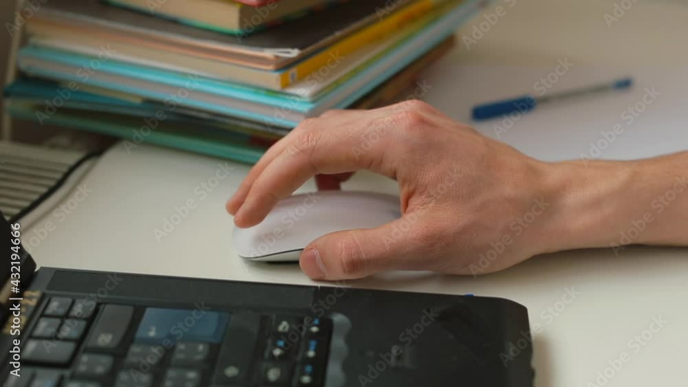 Poster the man's hand uses a computer mouse. he moves on the table, controls the application. stacked books