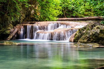 Fototapeta na wymiar Waterfall and blue emerald water color in Erawan national park. Erawan Waterfall, Beautiful nature rock waterfall steps in tropical rainforest at Kanchanaburi province, Thailand