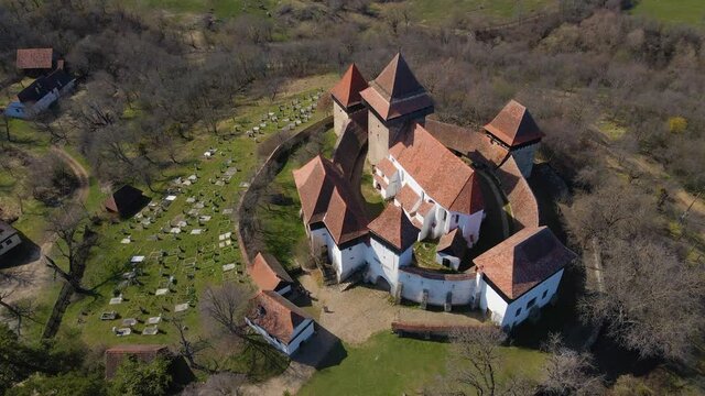 Aerial view of medieval fortified Church from Viscri, Romania. Birdseye view of the fortification while the drone is moving upwards slightly.