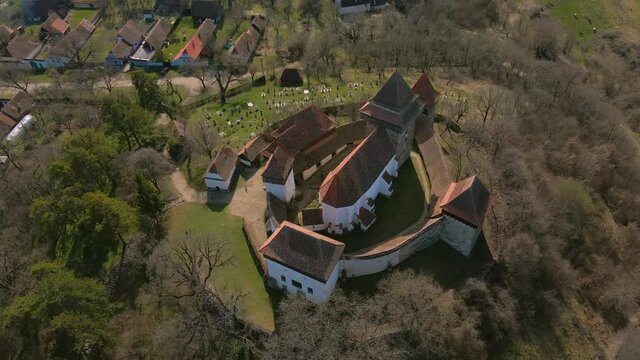 Aerial footage of a medieval fortified Church located in Viscri village, Brasov, Romania. Drone shot from a higher angle while circling anti clockwhise around the fortress.