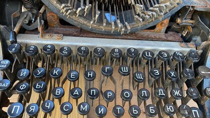 An old typewriter. Vintage styled retro machine. Close-up photo of vintage typewriter keys, small focus. Background of Russian printed letters