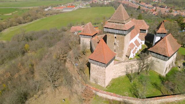Aerial footage of a medieval fortified Church located in Viscri village, Brasov, Romania. Drone shot from a higher angle while circling around the fortress.