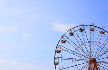 Sightseeing wheel in the amusement park on blue sky background with text space