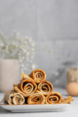 Crepes in rolls on white table. Beautiful breakfast background. Delicious oat pancakes, close up view. Sweet wraps. Organic, healthy dessert, food. Copy space.