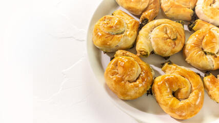 Mediterranean cuisine. Food banner with a national Greek causing with homemade pies with feta cheese and spinach on a white background with copy space. Healthy home baking pastries