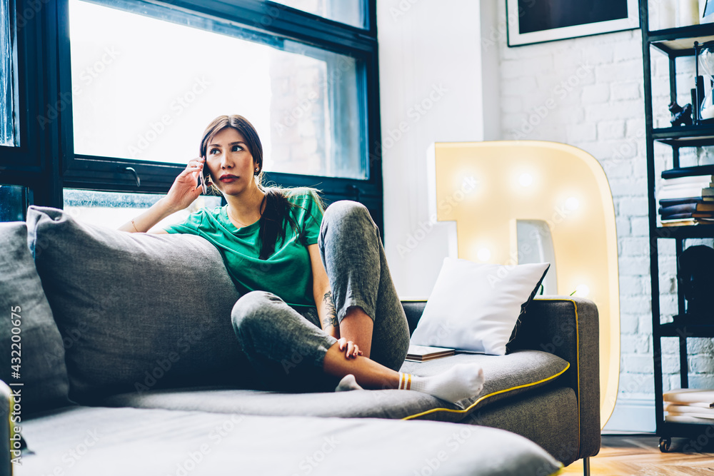 Aufkleber caucaisan hipster girl resting at comfortable home couch using cellphone application for calling to 