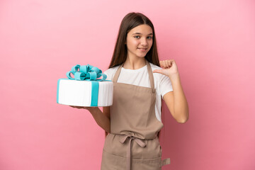 Little girl with a big cake over isolated pink background proud and self-satisfied