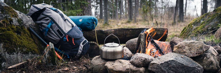 Backpack and Metal kettle on a campfire in the forest - 432201668