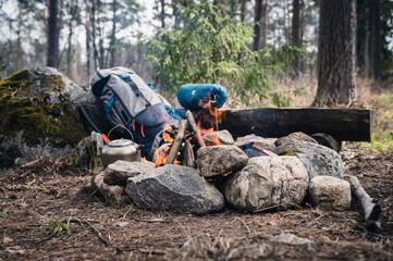 Backpack and Metal kettle on a campfire in the forest