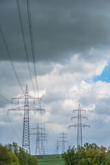 Strommasten einer Überlandleitung vor dunklem Wolkenhimmel