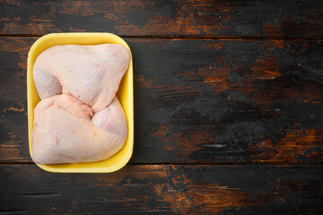 Family pack of fresh chicken legs, in Foam Tray Pack, on old dark  wooden table, top view flat lay, with copy space for text