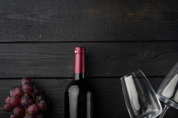 Red wine and grapes, on black wooden table background, top view flat lay, with copy space for text