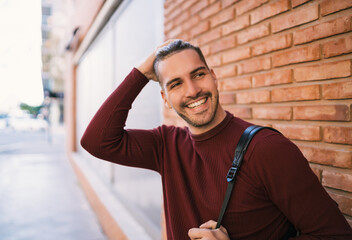 Young man against brick wall.