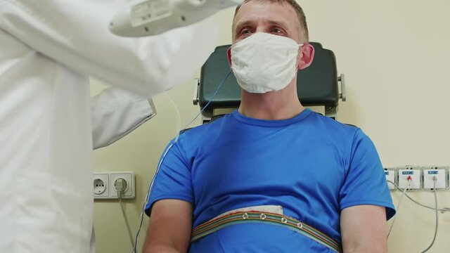 Doctor puts on a special cap for doing EEG. Patient wearing blue clothes is being examed