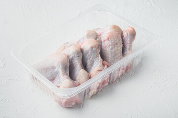 Fresh chicken wings package, on white stone  background