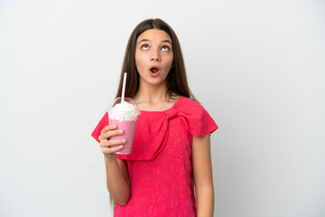 Little girl with strawberry milkshake over isolated white background looking up and with surprised expression