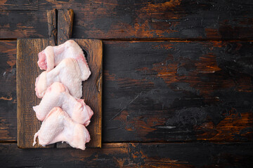 Uncooked chicken wings, on wooden cutting board, on old dark  wooden table background, top view flat lay, with copy space for text