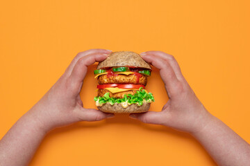 Veggie burger top view. Woman hands holding a vegan cheeseburger.