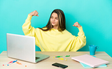 Little girl in a table with a laptop over isolated blue background doing strong gesture