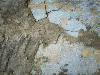 Weathered and cracked concrete wall maintained through time with blue lime and different mortar mixes. Peeling plaster from cement structure surface. Construction element, abstract texture background