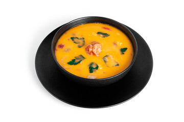 Soup with shrimps in a black deep dish isolated on a white background. Thai soup with seafood. Thai tom yum soup