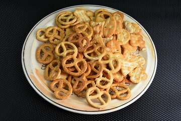 Mix of salty snacks (crackers and pretzels,bagels) in a bowl