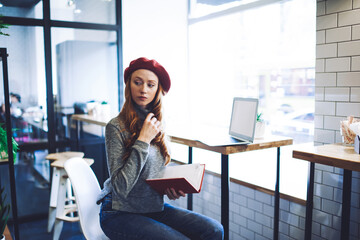 Serious woman with notebook working in light workspace