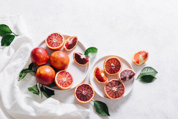 Composition of whole and sliced blood oranges in a plate on white table background. Flat lay, top view, copy space