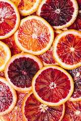 Bright colorful background of fresh ripe sliced blood oranges. Close up texture, flat lay, top view