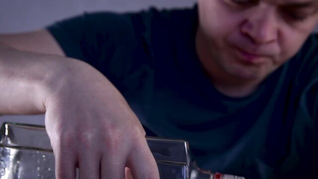 Alcoholic guy drinking cold transparent alcohol drink sake, tequila or rum. Man pouring up frozen vodka from bottle into shot glass .Alcohol dependence addiction
