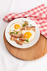 Fried eggs with bacon on a white plate