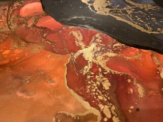 Abstract gold art with red, black and grey — fluid background with beautiful smudges and stains made with alcohol ink and golden pigment. Alcohol Ink texture resembles khokhloma, watercolor or aquarel