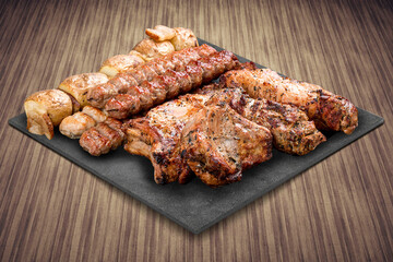 A selection of various barbecued gourmet meats on a black board with a rustic timber background. Pork neck, potatoes, kebab