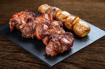 Stone board with different tasty cooked meat on wood background. Pork kebab, potatoes