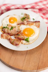 Fried eggs with bacon on a white plate