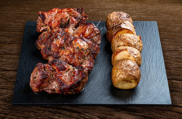 Stone board with different tasty cooked meat on wood background. Pork kebab, potatoes