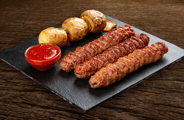 Stone board with different tasty cooked meat on wood background. Chicken kebab with baked potatoes