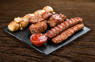 Stone board with different tasty cooked meat on wood background. Pork kebab, lyulya, potatoes.