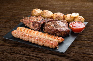 Stone board with different tasty cooked meat on wood background.  Veal kebab, lyulya, potatoes.