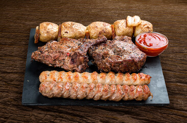Stone board with different tasty cooked meat on wood background.  Veal kebab, lyulya, potatoes.