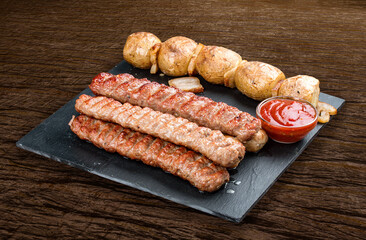 Stone board with different tasty cooked meat on wood background. Various kebab with baked potatoes