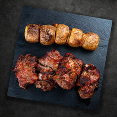 Stone board with different tasty cooked meat on wood background.  Veal kebab, lyulya, potatoes. Top view