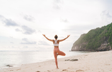 Fototapeta na wymiar Happy woman standing in yoga pose in front of sea
