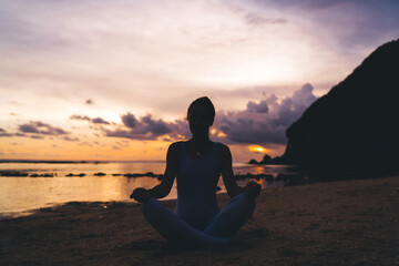 Unrecognizable woman meditating on seashore