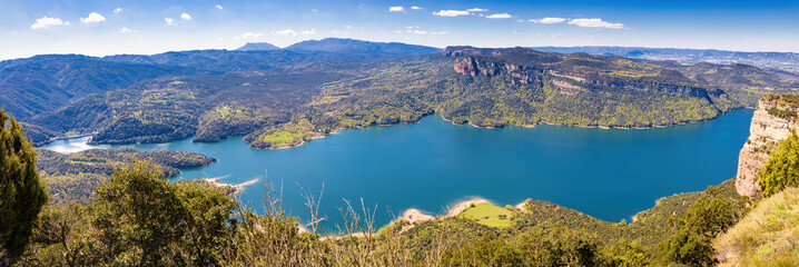 Fototapeta na wymiar Great aerial panorama of the Sau reservoir overlooking a large part of the reservoir, with the Munts cliffs and the Montseny mountain. Tavertet. Collsacabra, Osona, Catalonia, Spain
