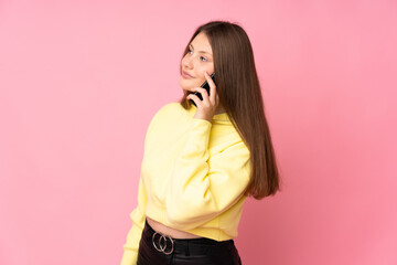 Fototapeta premium Teenager caucasian girl isolated on pink background keeping a conversation with the mobile phone with someone