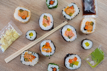 Sushi set of maki with chopsticks and various sauces on wooden background for menu